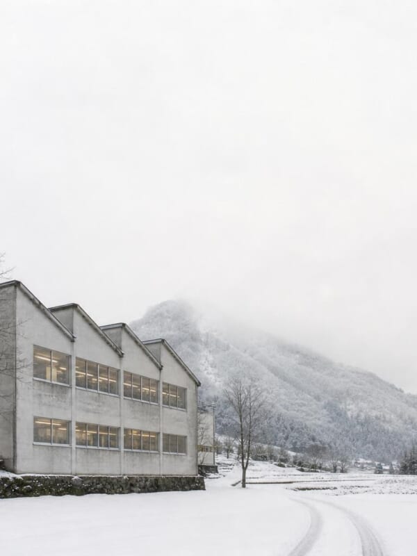 雪の山あいに建つ、のこぎり屋根の小さな編み物工場