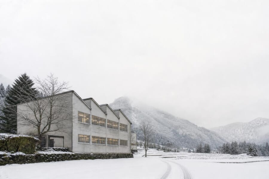 雪の山あいに建つ、のこぎり屋根の小さな編み物工場