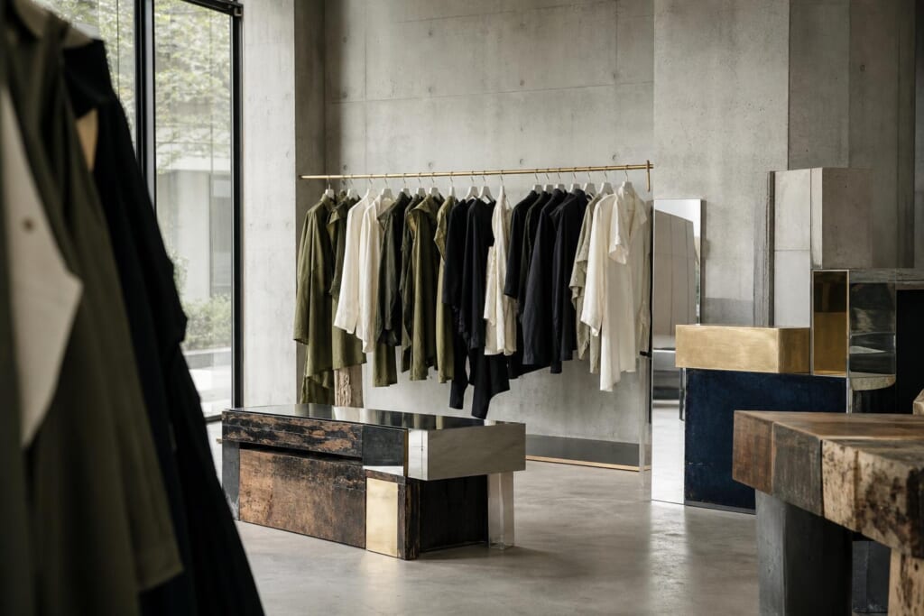 古い木、鉄、アクリル、鏡を組み合わせた家具のある、コンクリートの店内