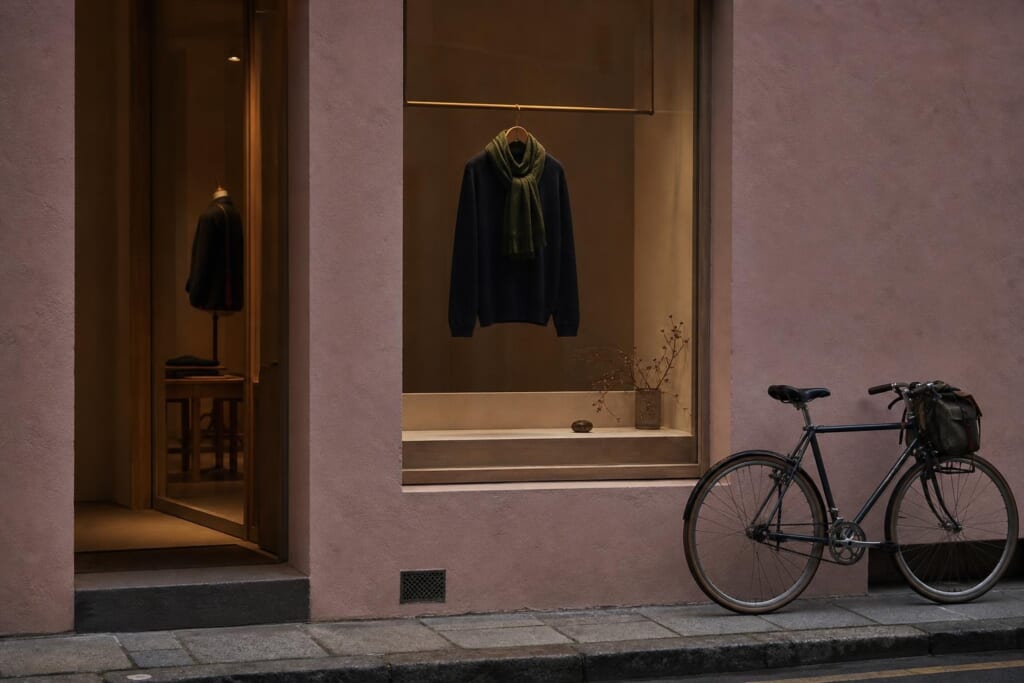 夕暮れの通りに面した、淡いピンクの壁の店と自転車