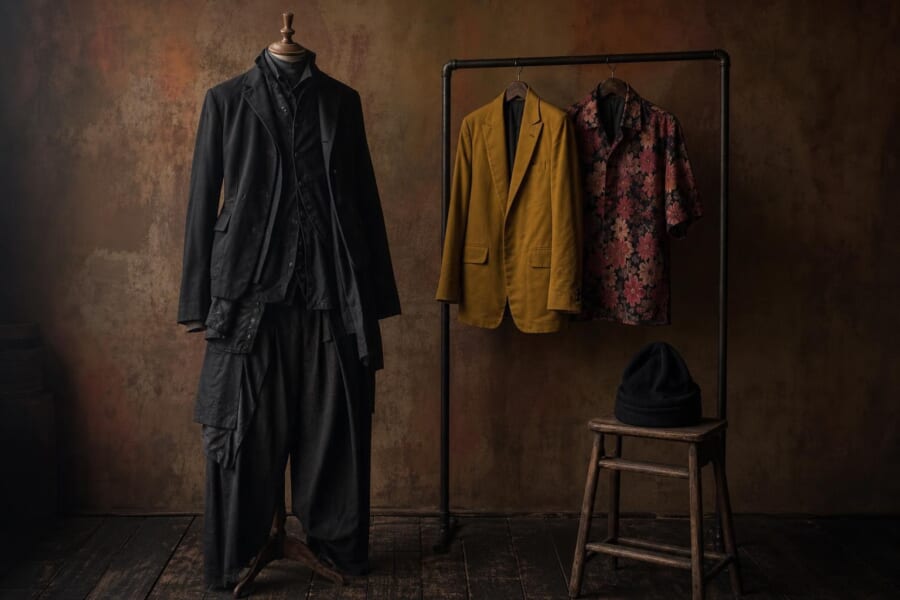 黒の重ね着の仕立てと、からし色のジャケット、赤い花柄のシャツ
